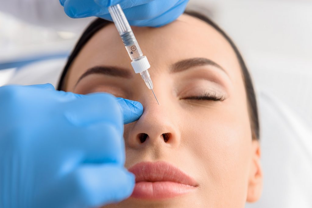 Woman receiving injection for a nonsurgical nose job (model)