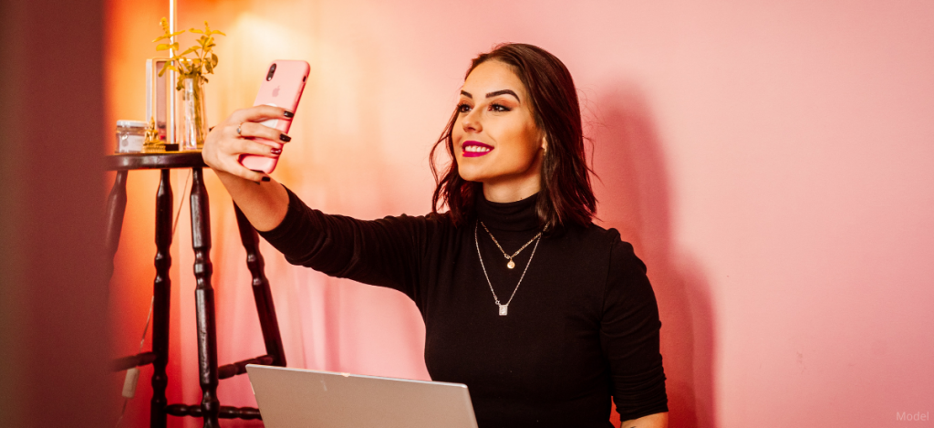 Woman taking selfie with her pink iphone