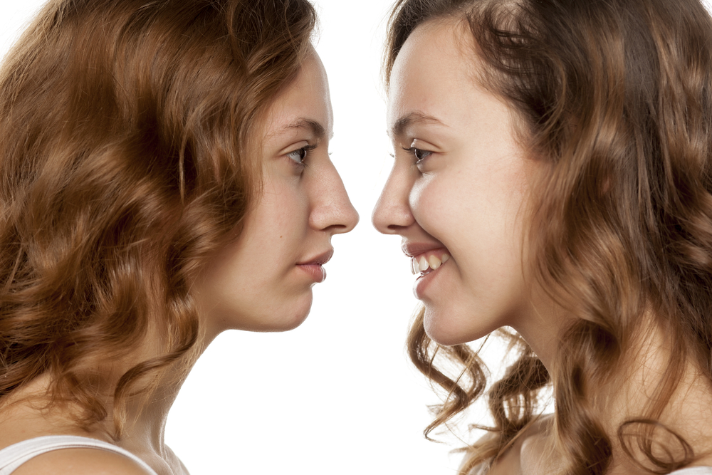 Before and after image of a woman looking at her reflection before and after a liquid rhinoplasty (model)