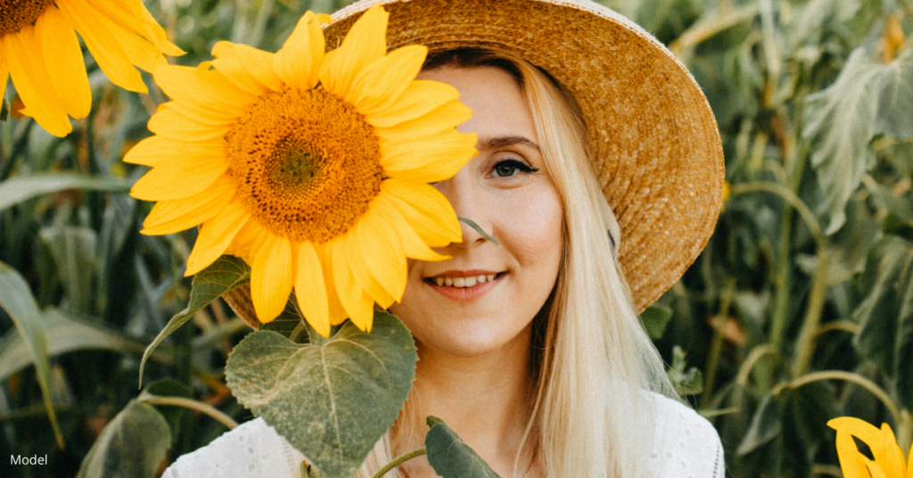 Young woman standing in sunflowers, considering laser skin resurfacing treatments in Denver, CO (model)