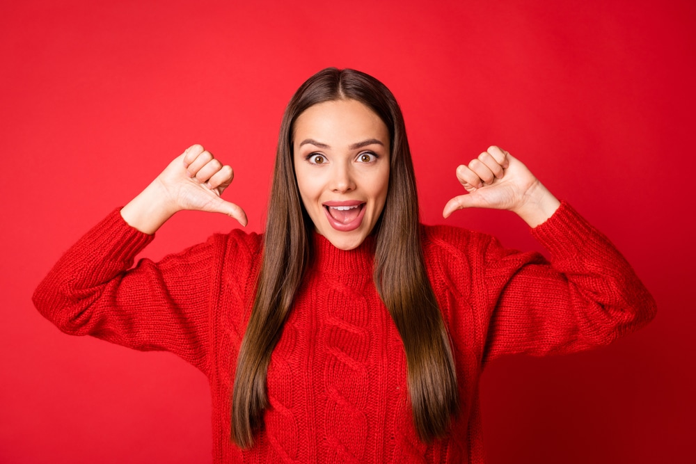 Model wearing red sweater pointing at herself
