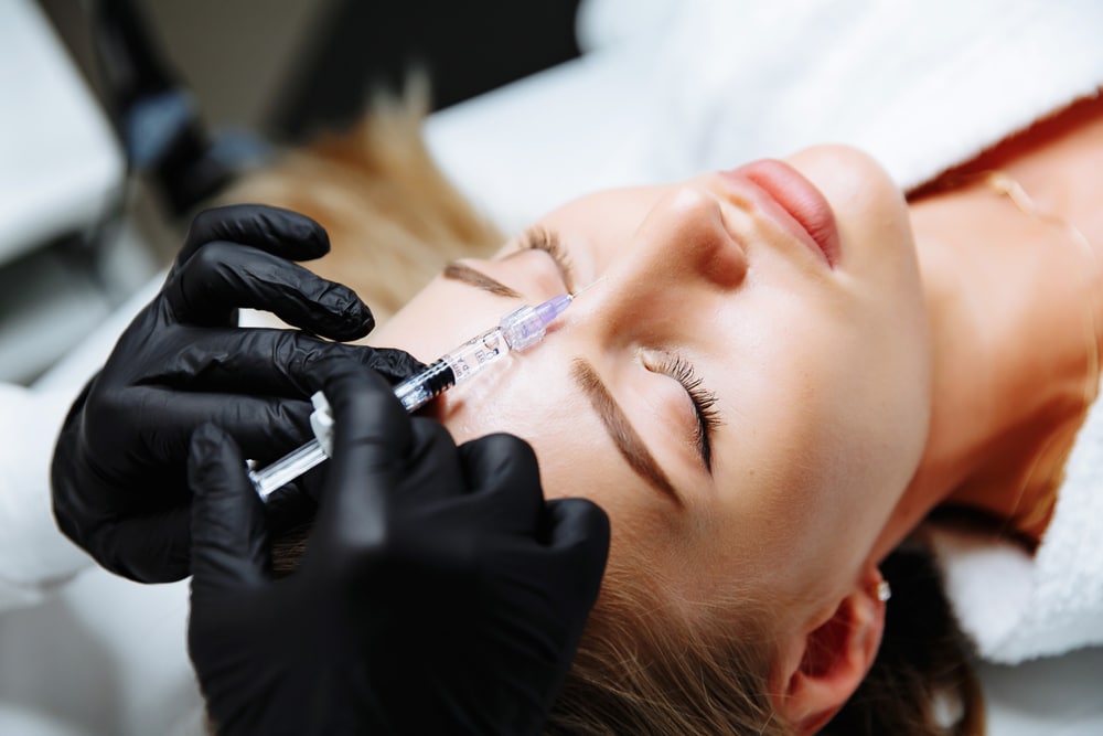 Woman laying down receiving a liquid rhinoplasty