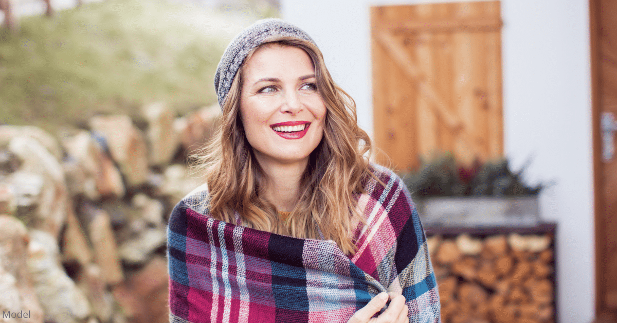 A woman smiling outside with a blanket near Denver, CO