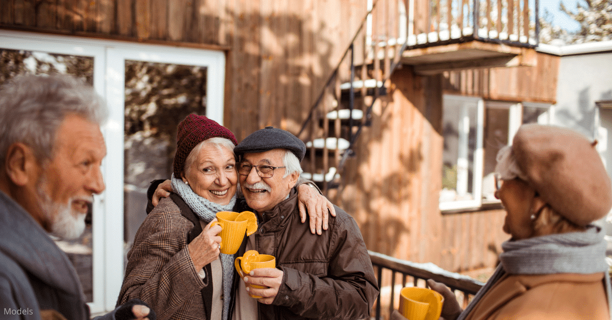 A mature couple outside in the snow drinking hot cider with friends near Denver, CO