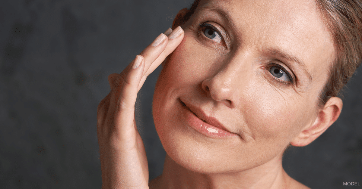 Middle-aged woman touching her right eye and smiling (model)