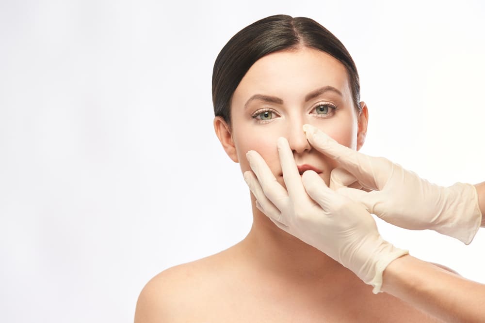 Woman's nose is closely examined by a plastic surgeon during a rhinoplasty consultation.